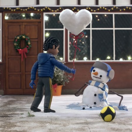 The boy gives a snowman a heart shaped snow balloon
