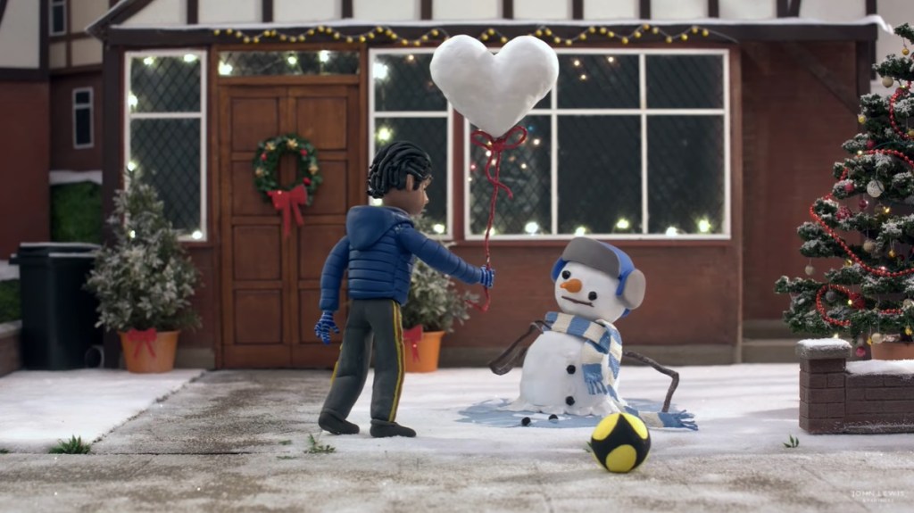 The boy gives a snowman a heart shaped snow balloon