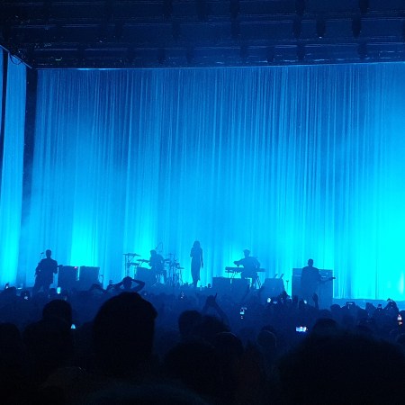Blue lighting floods the stage of Hammersmith Apollo so Wolf Alice appear in tinted silhouettes