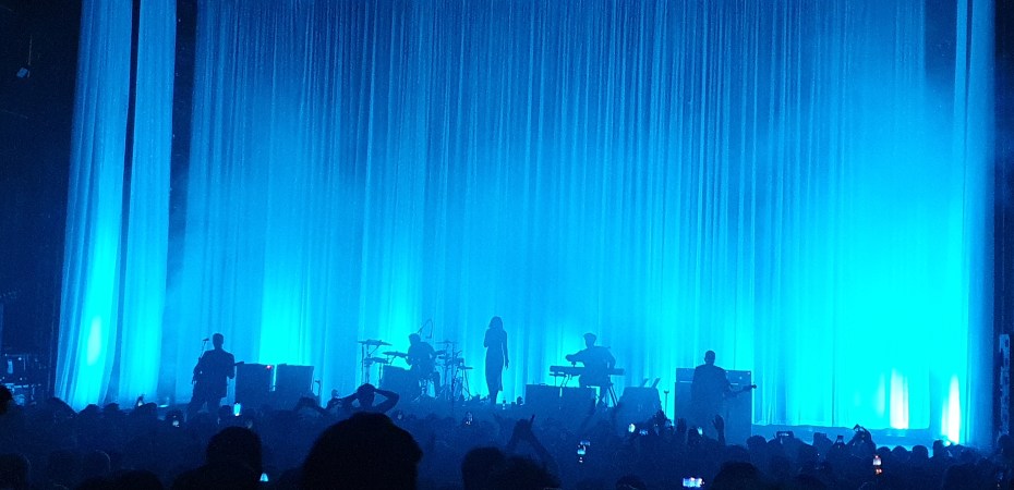 Blue lighting floods the stage of Hammersmith Apollo so Wolf Alice appear in tinted silhouettes