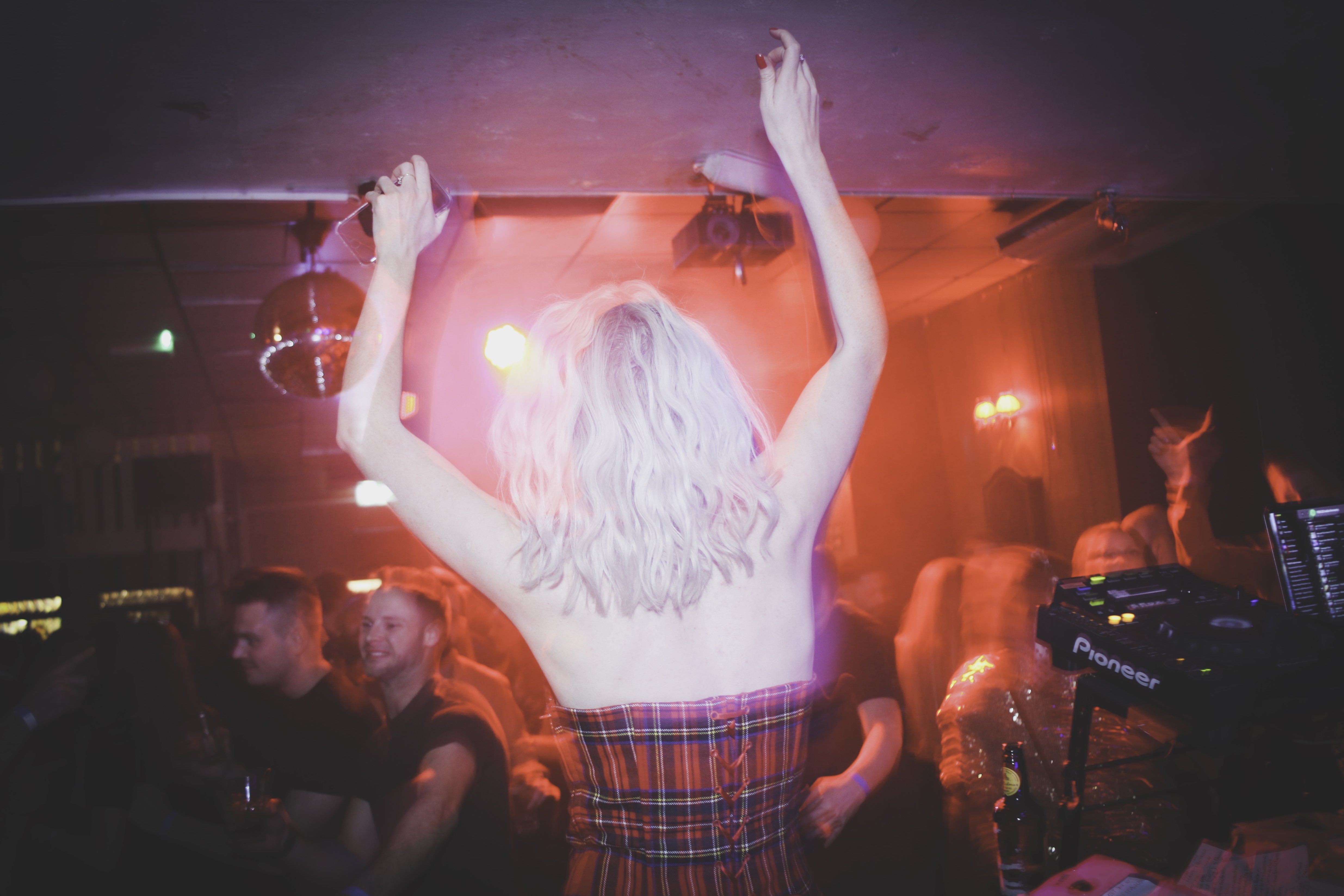 Alex Haddow dances on the stage while wearing a tartan dress at Indie Amnesty