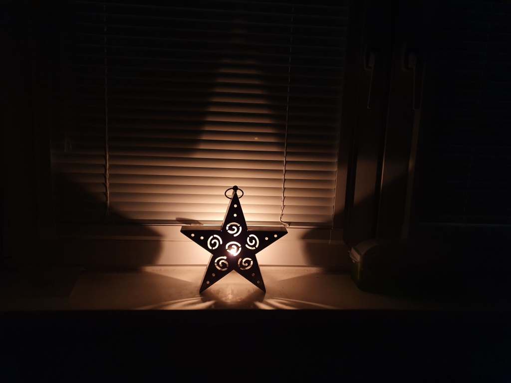 A star shaped candle holder is lit up by the flame